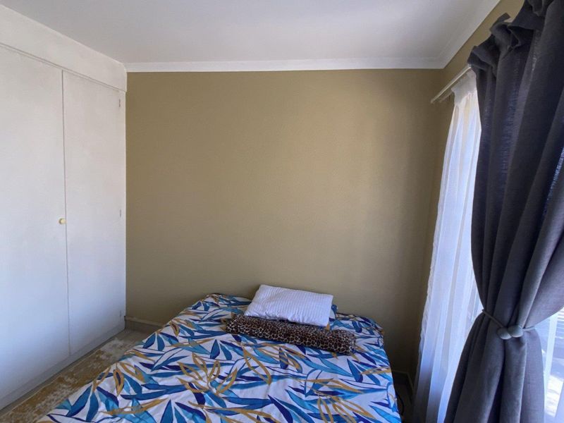 A functional bedroom featuring a built-in wardrobe and natural light from the window, providing a comfortable space for rest.