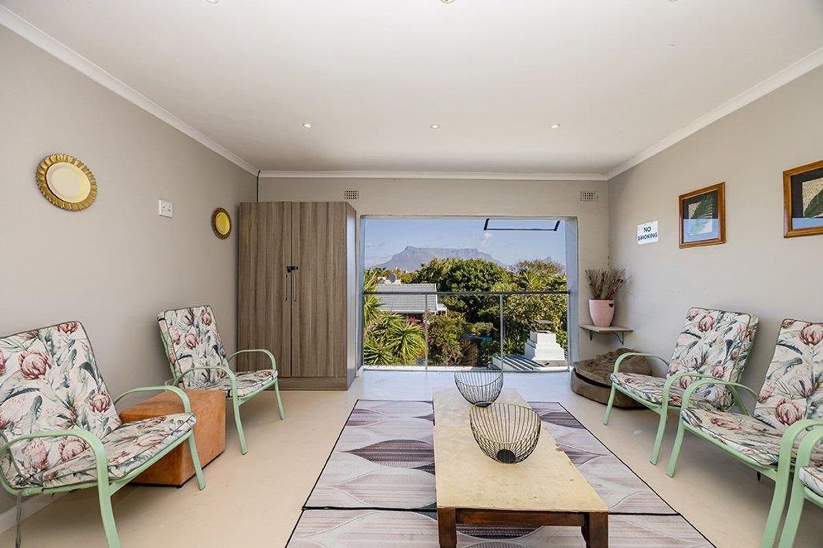 A bright living area featuring recessed lighting, a built-in cupboard, and a glass balustrade opening to a balcony with scenic mountain views.