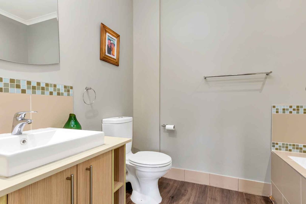 A clean and functional bathroom featuring a modern vanity, toilet, and tiled splashbacks with a neutral color palette.