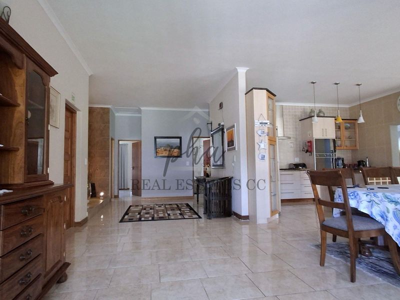 Spacious open-plan living and dining area featuring tiled flooring and an integrated kitchen with built-in cabinetry and modern lighting fixtures.