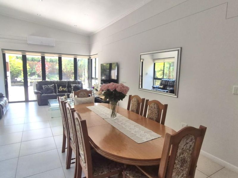 Spacious open-plan living and dining area featuring tiled flooring, recessed lighting, a split-system air conditioner, and large bi-fold doors leading to the outdoors.