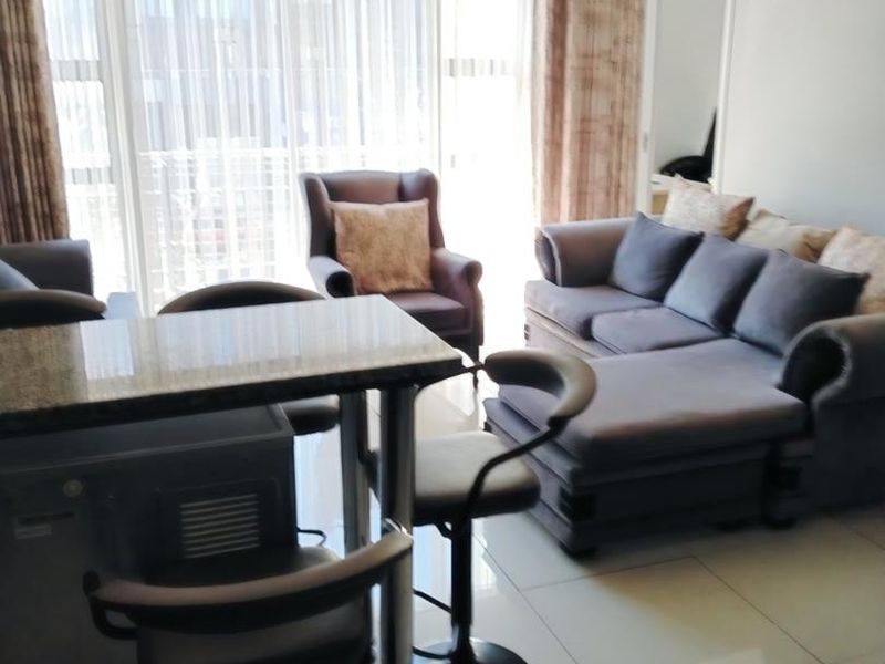 Open plan living area featuring large format floor tiles and a sliding glass door providing access to the balcony.