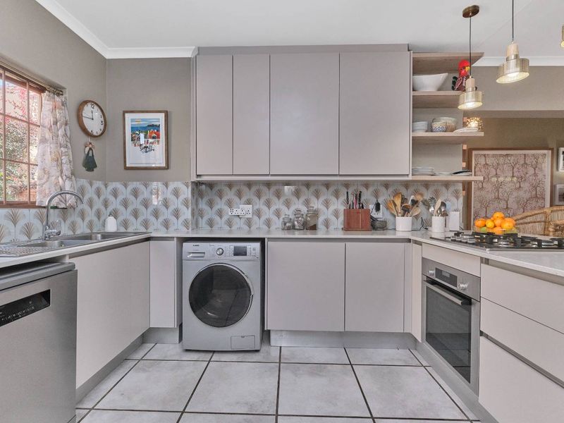 Modern kitchen featuring sleek cabinetry, stone countertops, integrated appliances, a gas hob, and stylish decorative backsplash tiling.