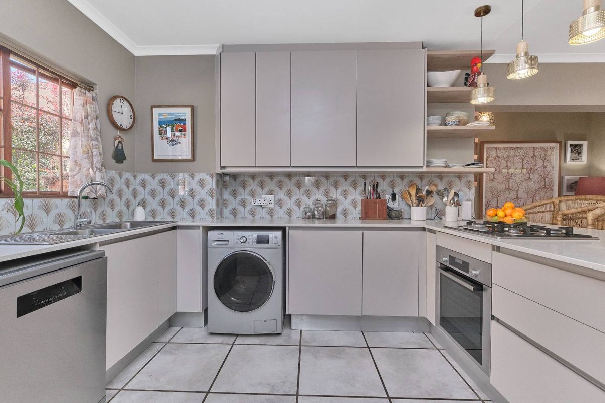 Modern kitchen featuring sleek cabinetry, stone countertops, integrated appliances, a gas hob, and stylish decorative backsplash tiling.