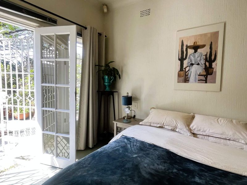 A bright bedroom featuring classic french doors that open directly onto a private patio area, providing seamless indoor-outdoor flow.
