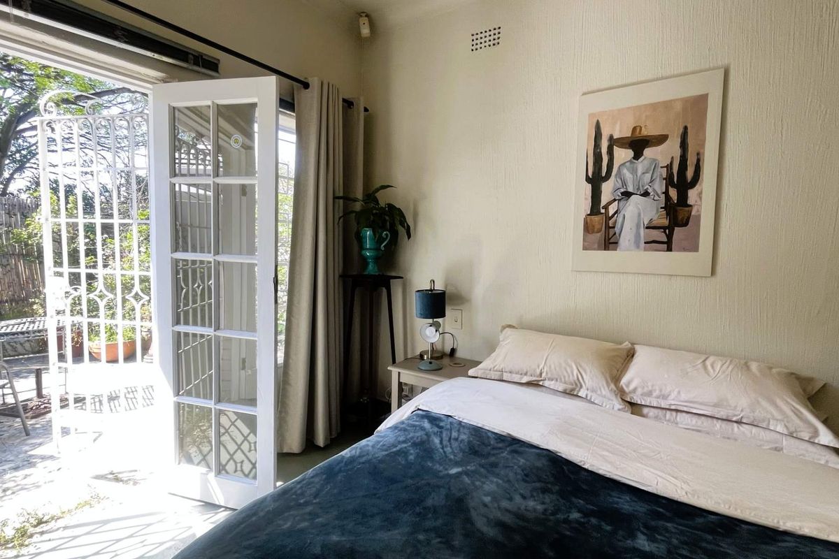 A bright bedroom featuring classic french doors that open directly onto a private patio area, providing seamless indoor-outdoor flow.