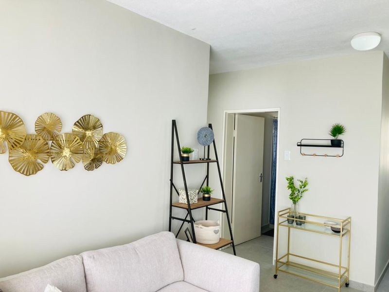 A bright and neutral living area featuring tiled flooring and a flush mount ceiling light, providing a clean and welcoming space.