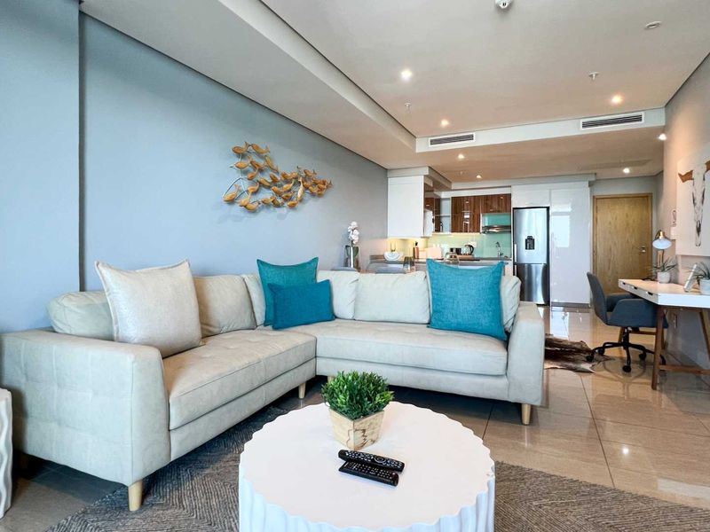 Modern open-plan living area featuring tiled floors, recessed ceiling lighting, ducted air conditioning, and a sleek integrated kitchen.