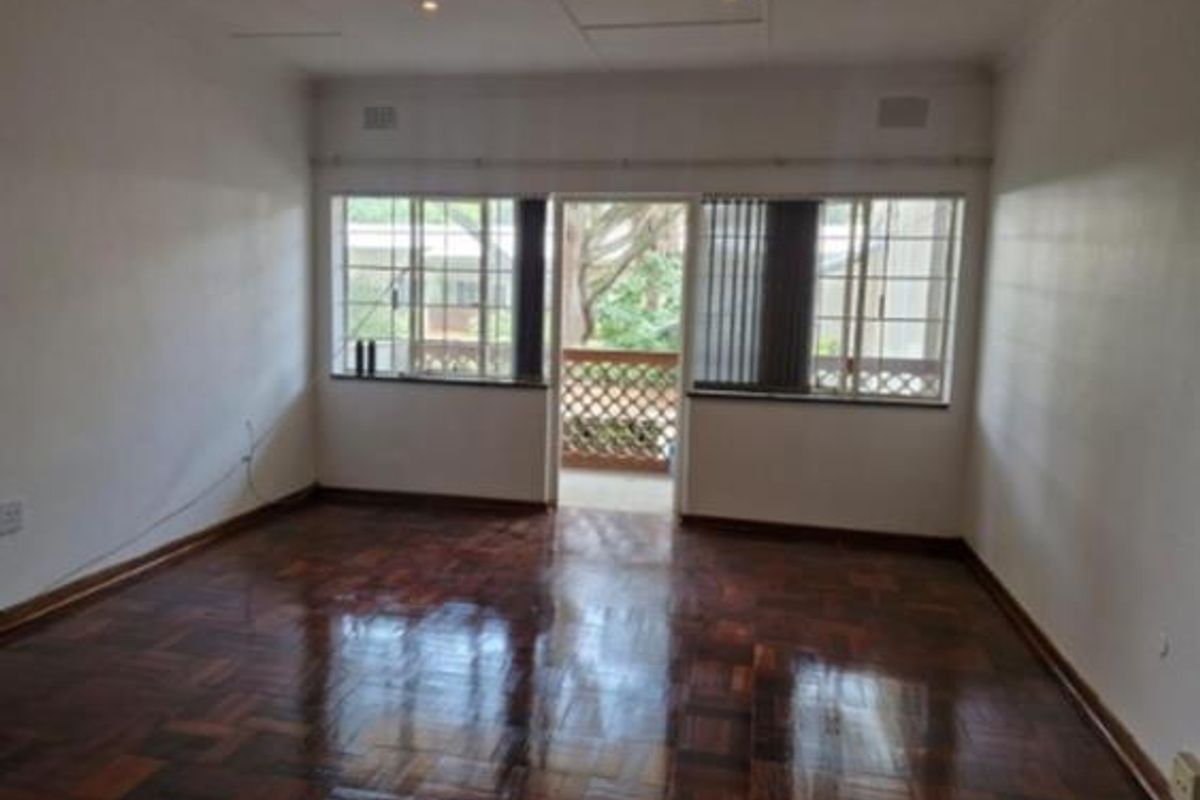 Spacious living area featuring polished parquet flooring, recessed lighting, and direct access to a balcony through a sliding door.