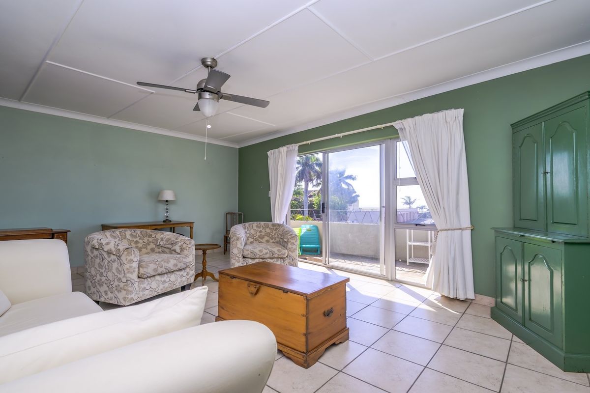 Spacious living room featuring tiled flooring, a ceiling fan, and large sliding glass doors that provide access to an outdoor balcony area.