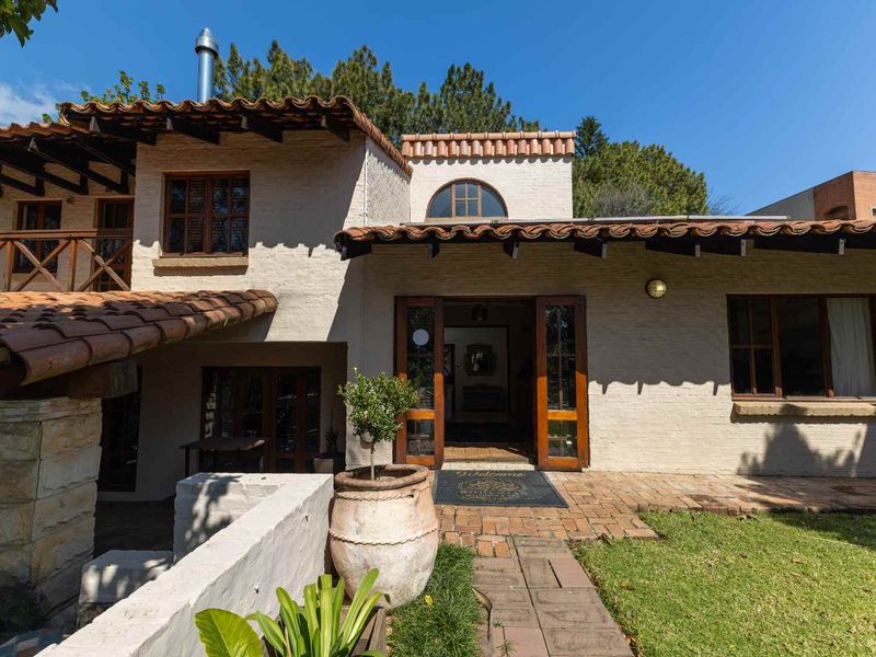 A charming front facade featuring traditional terracotta roof tiles, textured masonry walls, and timber-framed entrance doors leading into the home.