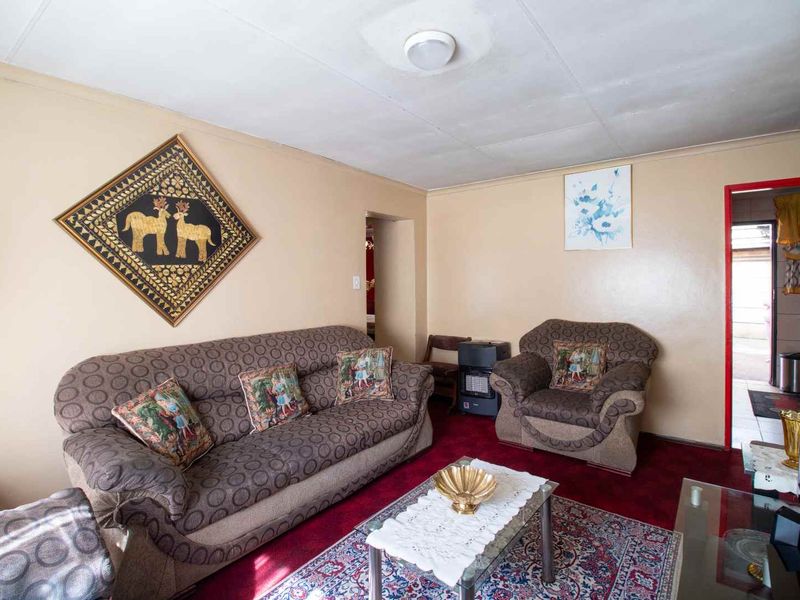 A living room featuring a coved ceiling and dated finishes, offering a functional space that could benefit from modern updates.