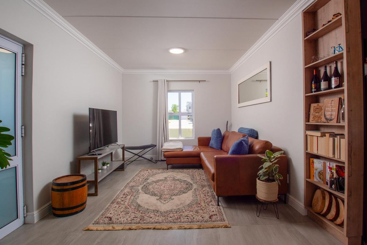 A well-maintained living room featuring neutral walls, crown molding, and light-toned wood-look flooring, providing a clean and inviting space.