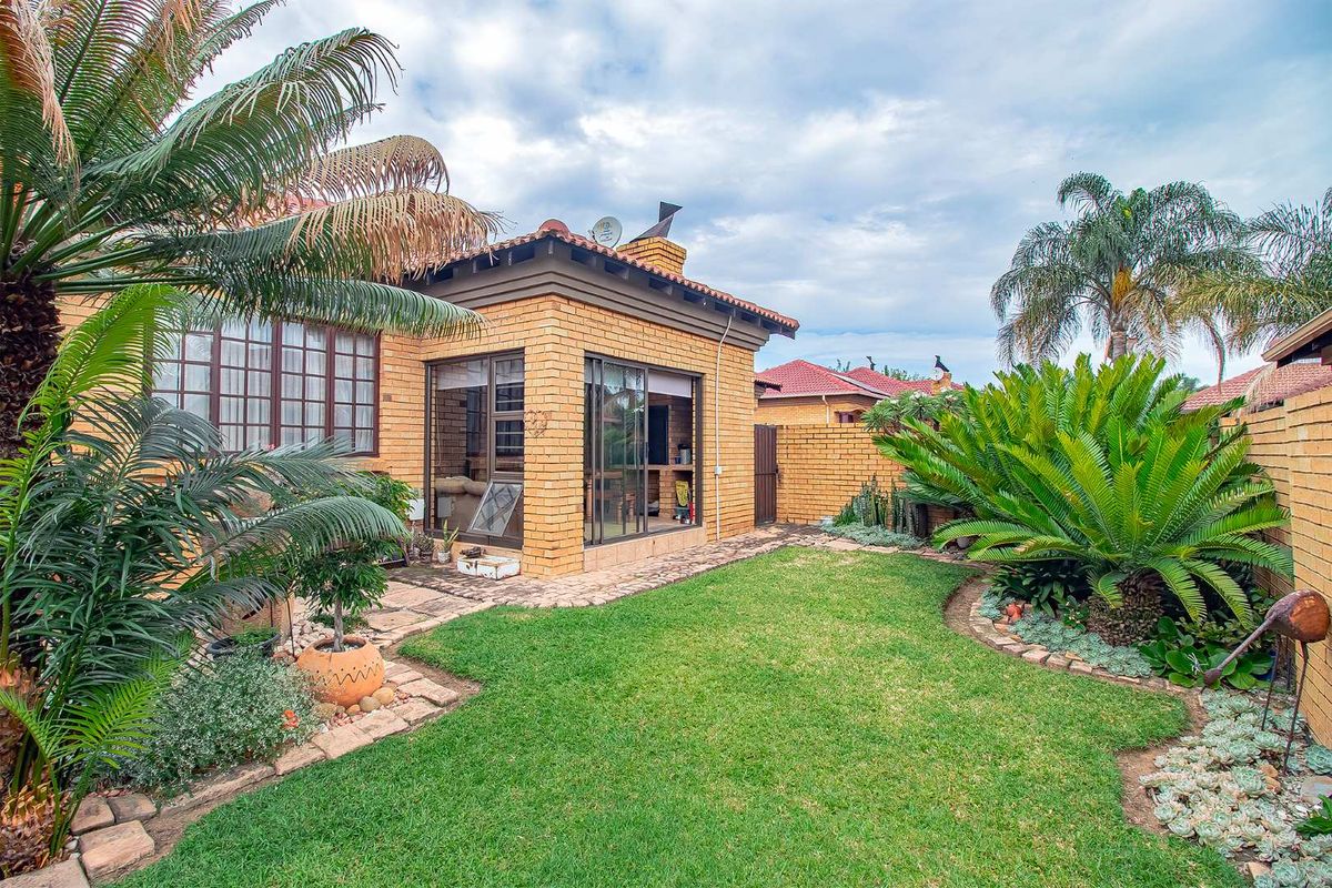 A well-maintained rear garden featuring a brick-built exterior, paved walkway, and established landscaping, providing a private outdoor space.