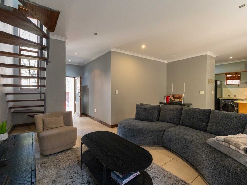 Open plan living area featuring a modern spiral staircase, tiled flooring, recessed lighting, and an adjacent kitchen with built-in cabinetry.