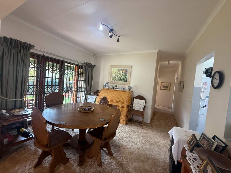 Dining room featuring carpet flooring, coved ceilings, and sliding glass doors with security gates leading to the exterior.