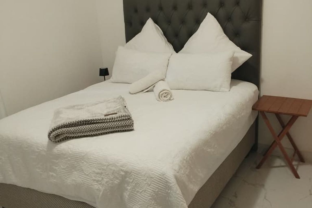A clean and simple bedroom featuring light-colored tiled flooring and neutral wall finishes.