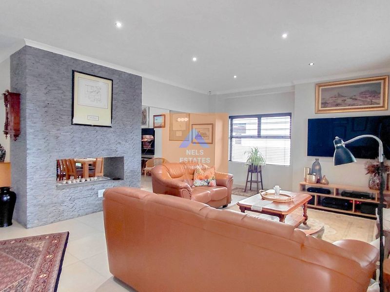 Spacious living room featuring a modern stone-clad fireplace, neutral tiled flooring, and recessed downlighting, creating a comfortable and inviting atmosphere.