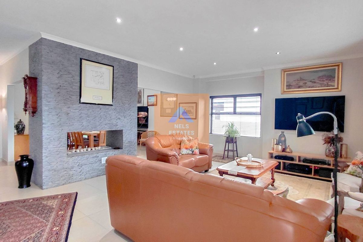Spacious living room featuring a modern stone-clad fireplace, neutral tiled flooring, and recessed downlighting, creating a comfortable and inviting atmosphere.