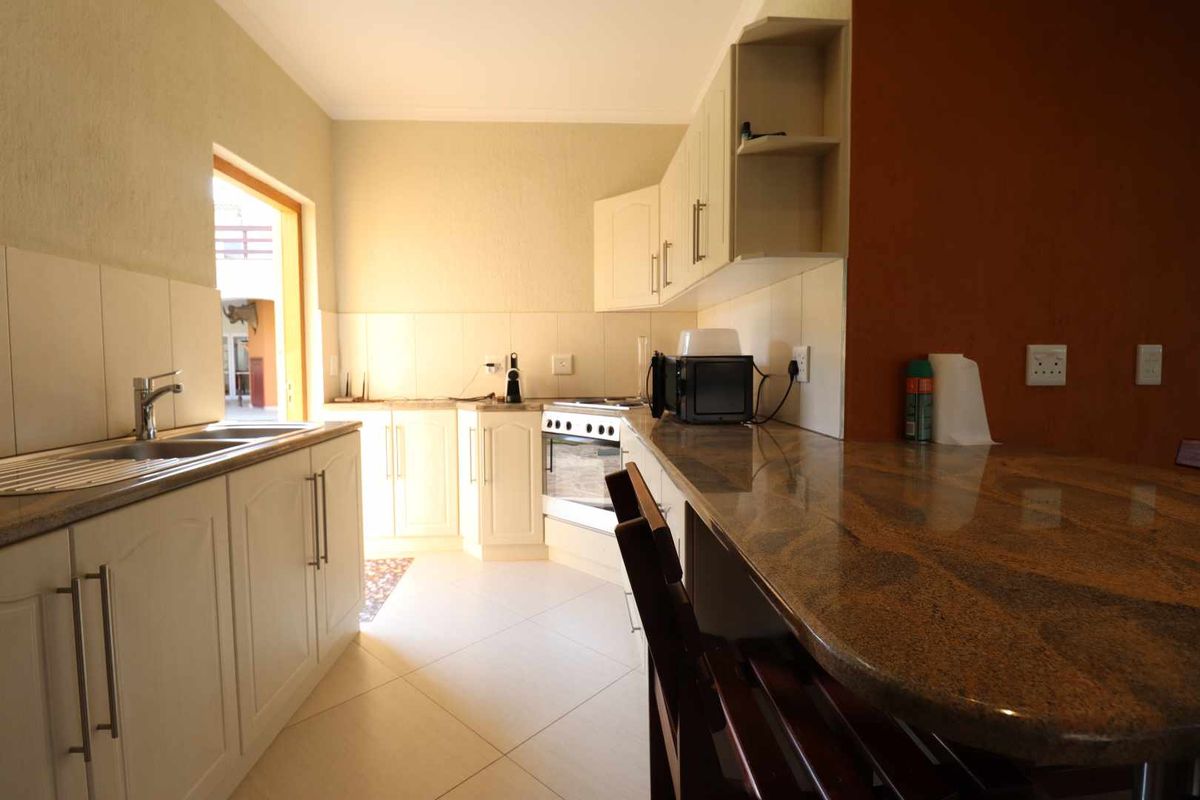 A functional kitchen featuring white cabinetry, granite countertops, a breakfast bar, and a built-in oven with a hob.