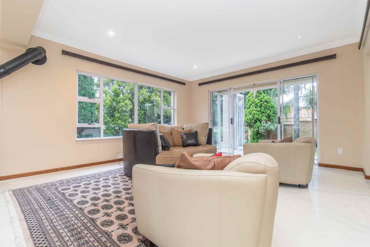 Spacious living room featuring large windows, sliding glass doors leading to the garden, and a built-in fireplace flue.