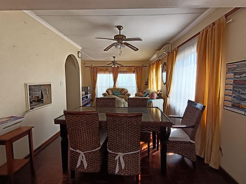 Open-plan living and dining area featuring parquet flooring, dual ceiling fans, and a wall-mounted air conditioning unit.