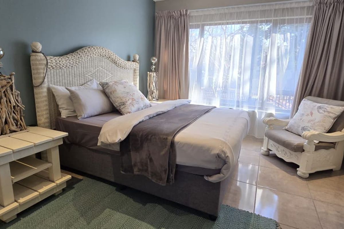A well-maintained bedroom featuring tiled flooring and large windows with curtain tracks, offering a comfortable and functional living space.