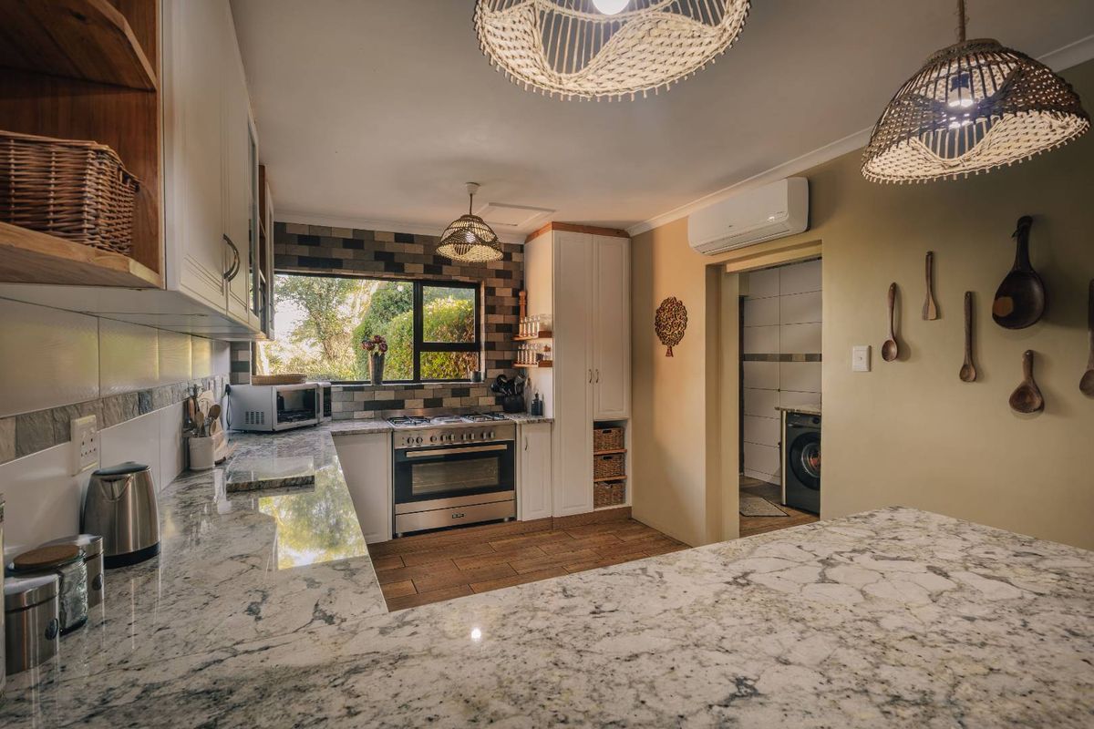 Modern kitchen featuring granite countertops, built-in oven with gas hob, tiled backsplash, and ample cabinetry, with an adjacent laundry area visible.