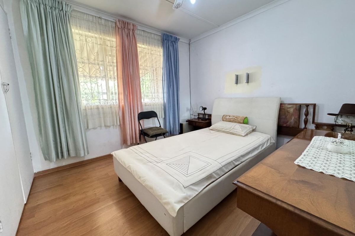 A bedroom featuring laminate flooring, security bars on windows, and neutral wall finishes.