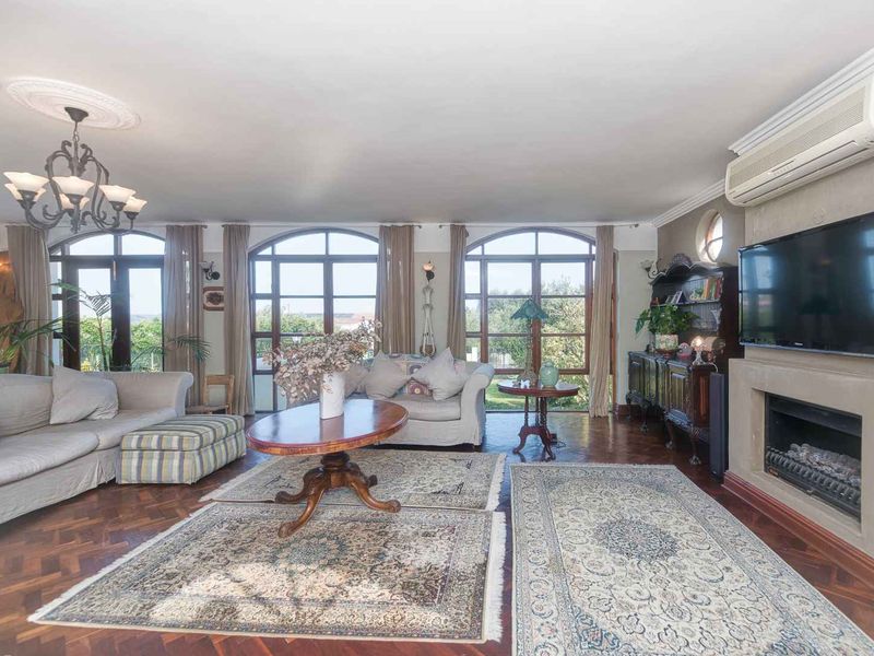 Spacious living room featuring classic herringbone parquet flooring, a built-in fireplace, and large arched windows that provide ample natural light and garden views.