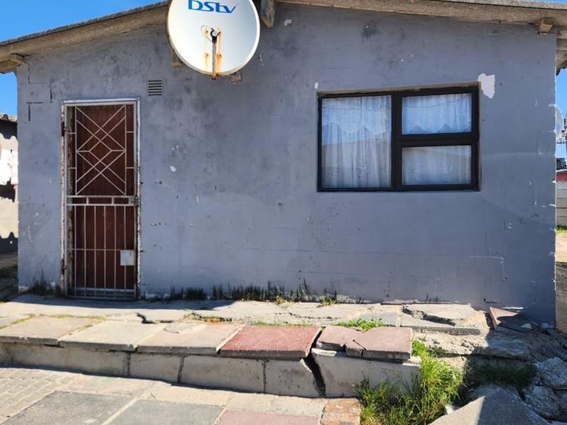 Front exterior view of a single-story house featuring a security gate, satellite dish, and damaged concrete steps requiring maintenance.