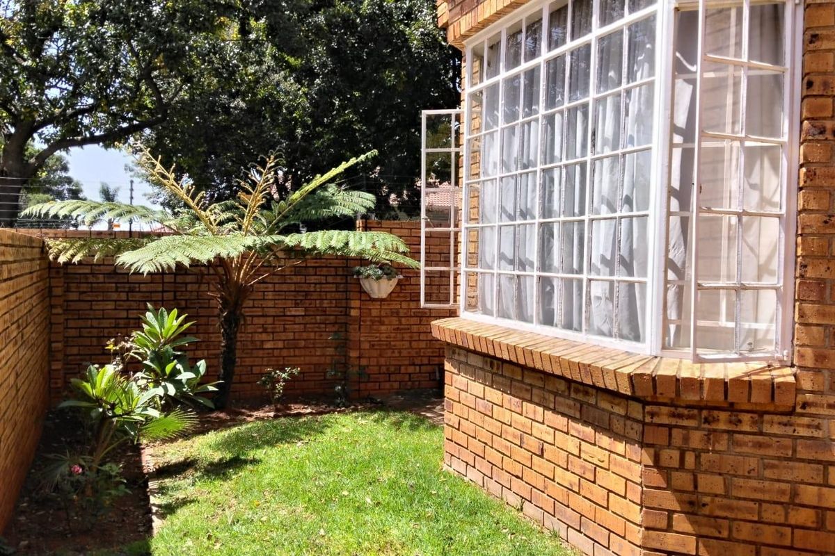 A private rear garden area featuring a face brick townhouse exterior with a classic bay window and secure boundary walling.