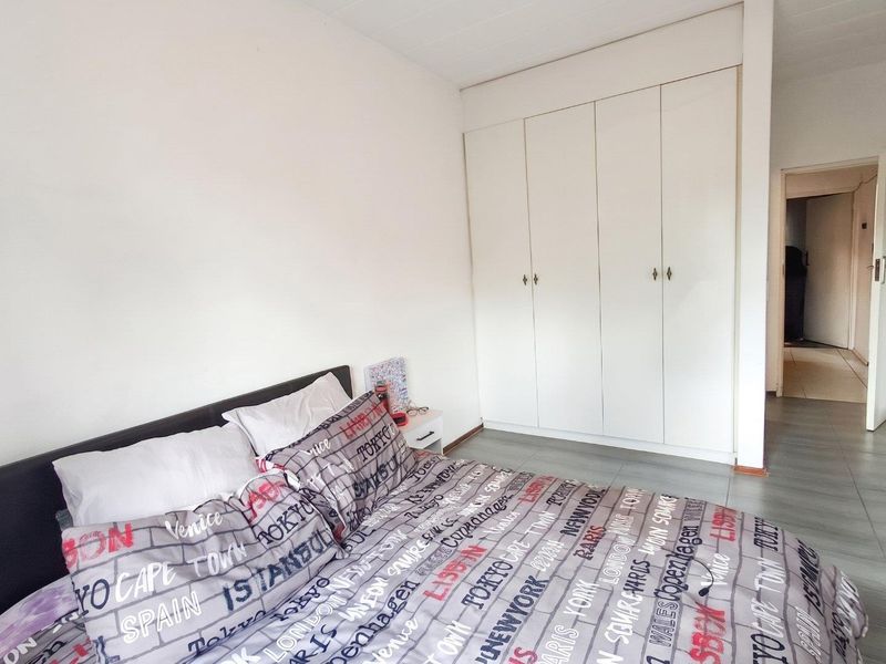 A functional bedroom featuring built-in cupboards and tiled flooring, offering a clean and neutral space ready for personalization.