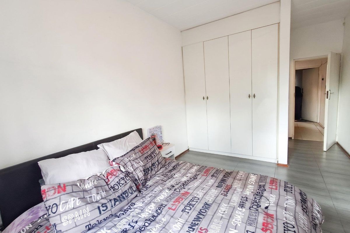 A functional bedroom featuring built-in cupboards and tiled flooring, offering a clean and neutral space ready for personalization.