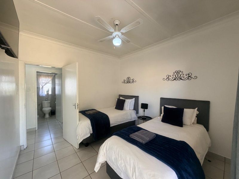 A functional bedroom featuring tiled flooring, a ceiling fan, and direct access to an en-suite bathroom.