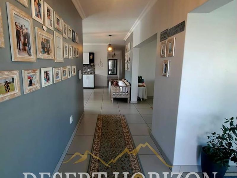 A well-lit hallway featuring neutral wall tones, tiled flooring, and decorative cornice detailing, providing a clean transition between living spaces.