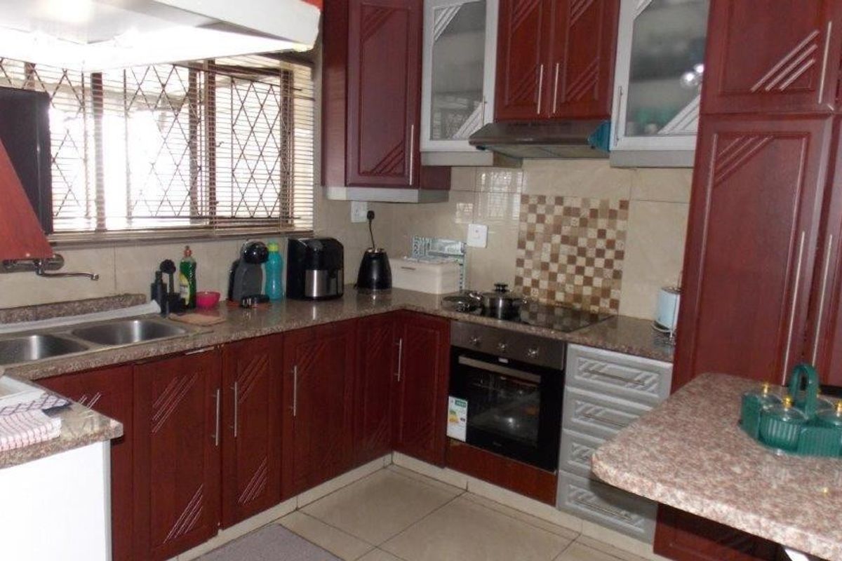 A functional kitchen featuring dark wood cabinetry, laminate countertops, a built-in oven with hob, and tiled splashbacks.