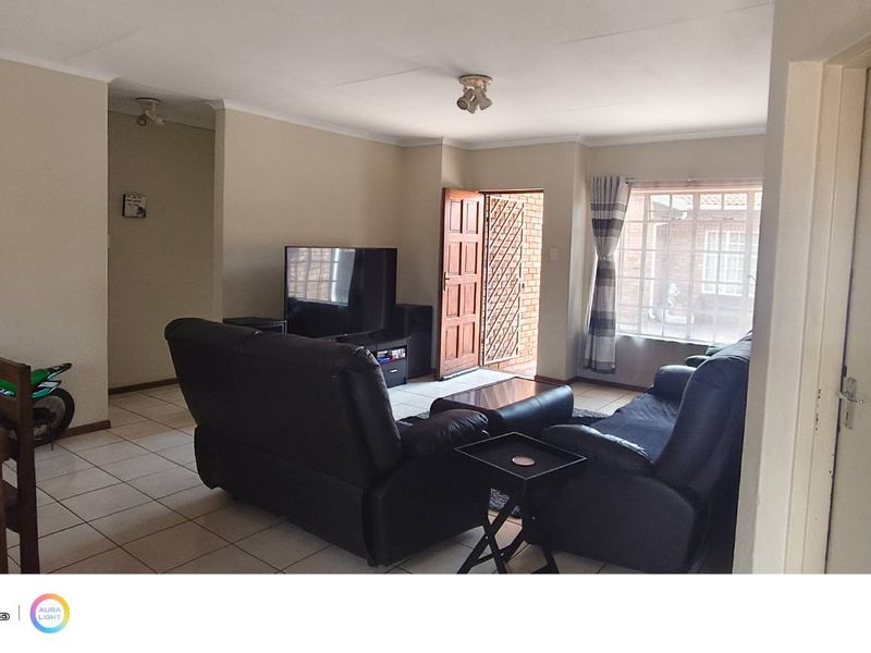 Open-plan living and dining area featuring tiled flooring, neutral wall tones, and direct access to the exterior through a security gate.