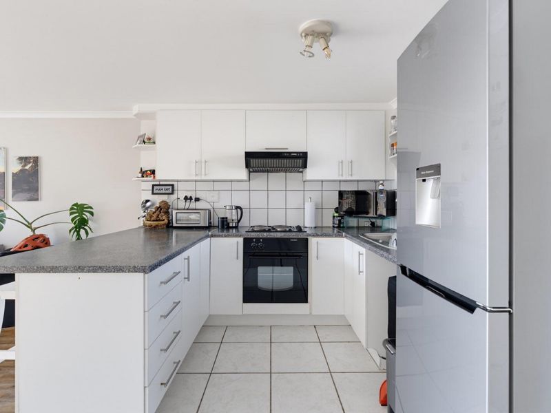 A functional kitchen featuring white cabinetry, laminate countertops, a built-in oven with gas hob, and tiled flooring.