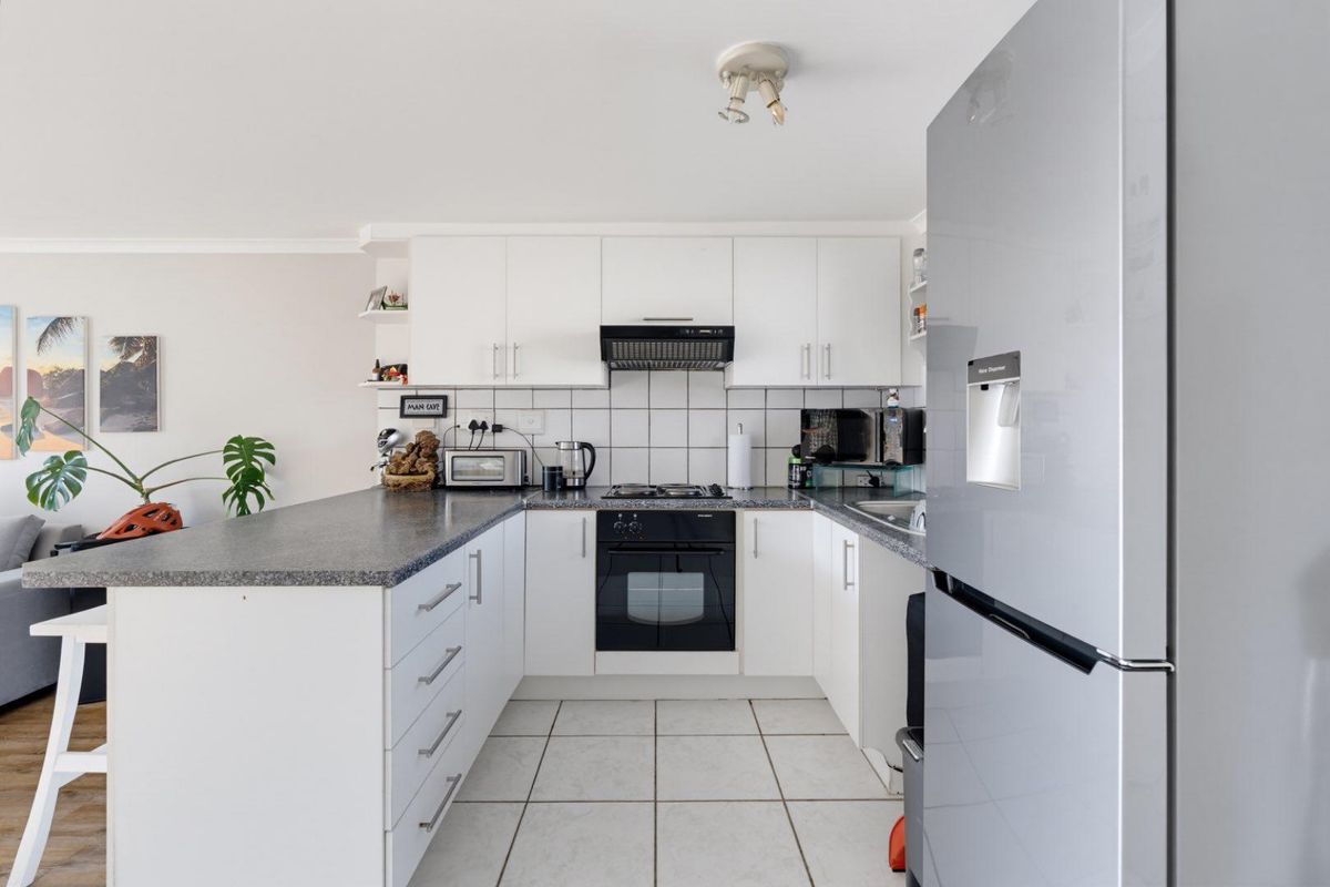 A functional kitchen featuring white cabinetry, laminate countertops, a built-in oven with gas hob, and tiled flooring.