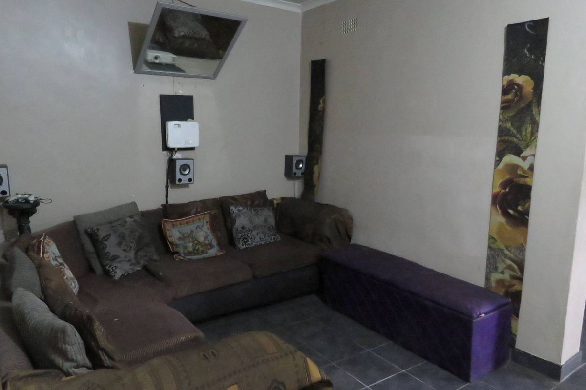 A living room area featuring tiled flooring and wall-mounted audio-visual equipment, providing a functional space for entertainment.