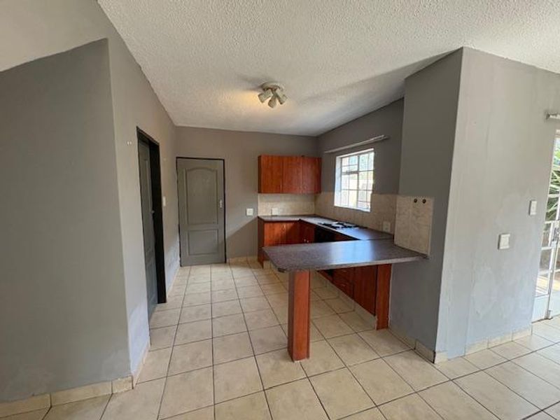 A functional kitchen featuring wooden cabinetry, a breakfast bar, tiled flooring, and a built-in hob, offering a practical layout for daily use.