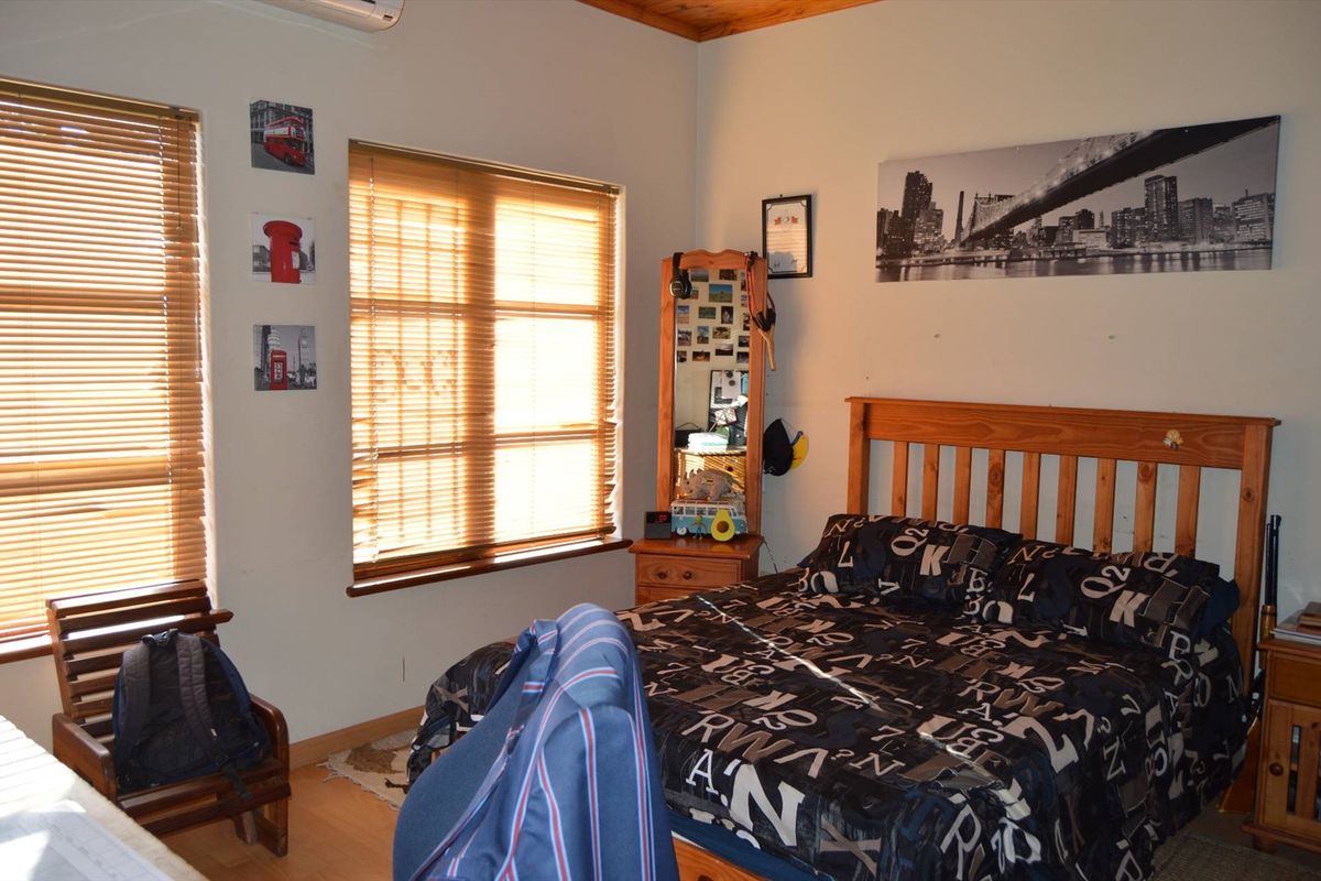 A bedroom featuring timber-framed windows with fitted blinds, laminate flooring, and a timber ceiling finish.