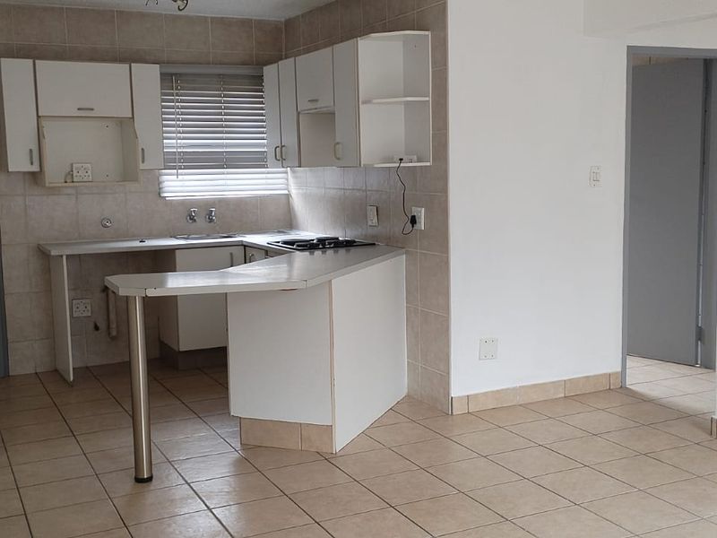 A functional kitchen featuring tiled flooring, built-in cabinetry, a breakfast bar, and a tiled backsplash, offering a clean and practical layout.