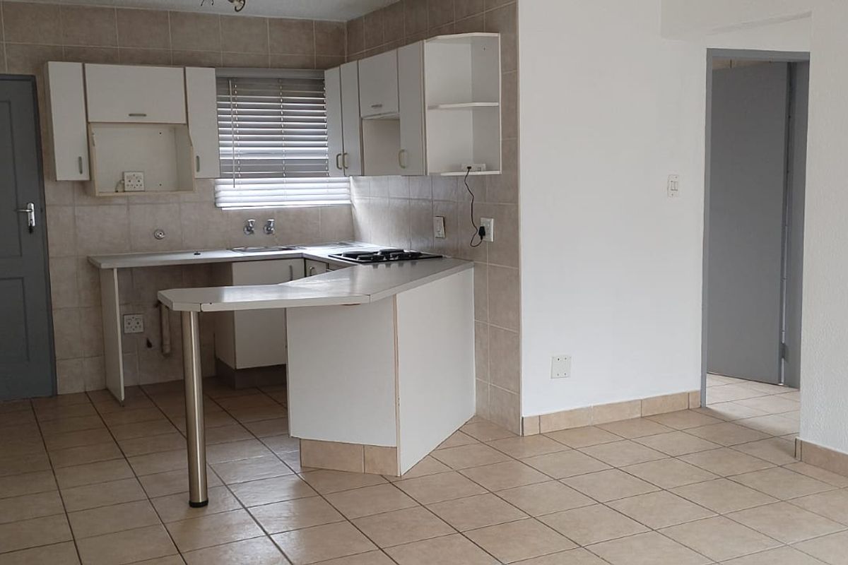 A functional kitchen featuring tiled flooring, built-in cabinetry, a breakfast bar, and a tiled backsplash, offering a clean and practical layout.