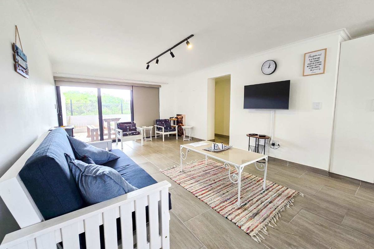 A bright and open living area featuring tiled flooring, track lighting, and large sliding glass doors leading to an outdoor patio space.