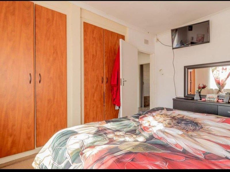 A bedroom featuring built-in wooden cupboards, carpeted flooring, and coved ceilings, requiring some cosmetic updates to improve its overall condition.