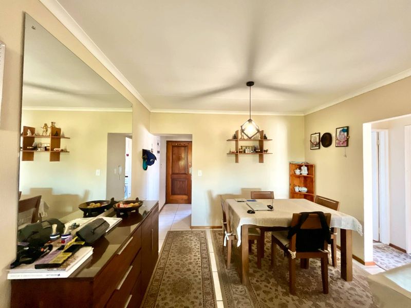 A functional dining area featuring tiled flooring, a central pendant light, and a solid wood entrance door, offering a neutral canvas for updates.
