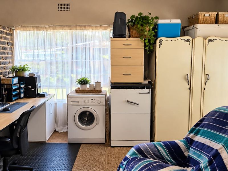 A multi-purpose utility space featuring an exposed brick wall, built-in desk area, and integrated laundry facilities.