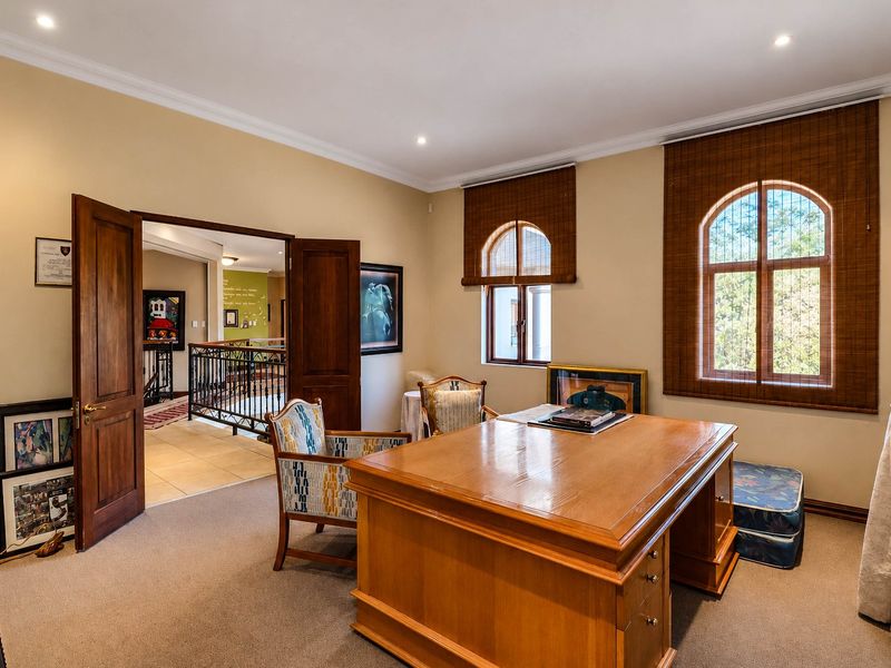A well-lit home office featuring arched windows, neutral carpeting, and elegant timber double doors leading to the hallway.